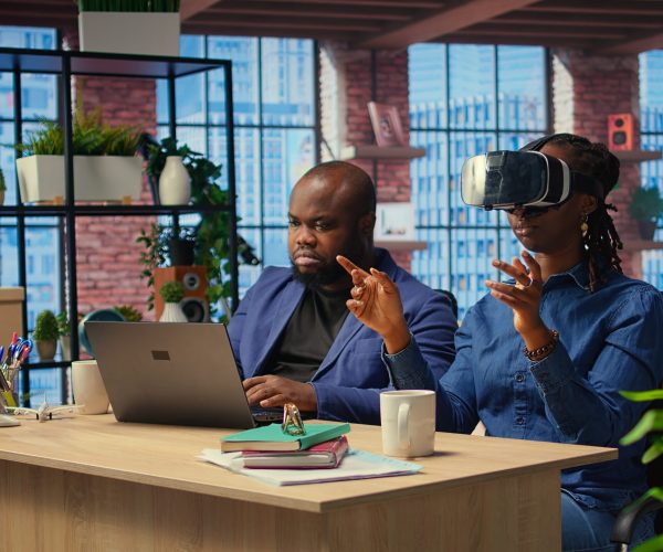 Self employed couple navigates remote work with advanced technology Self employed couple navigates remote work with advanced technology, young man explores 3D simulations through a VR headset. AI, metaverse and innovation in modern careers. Camera A.